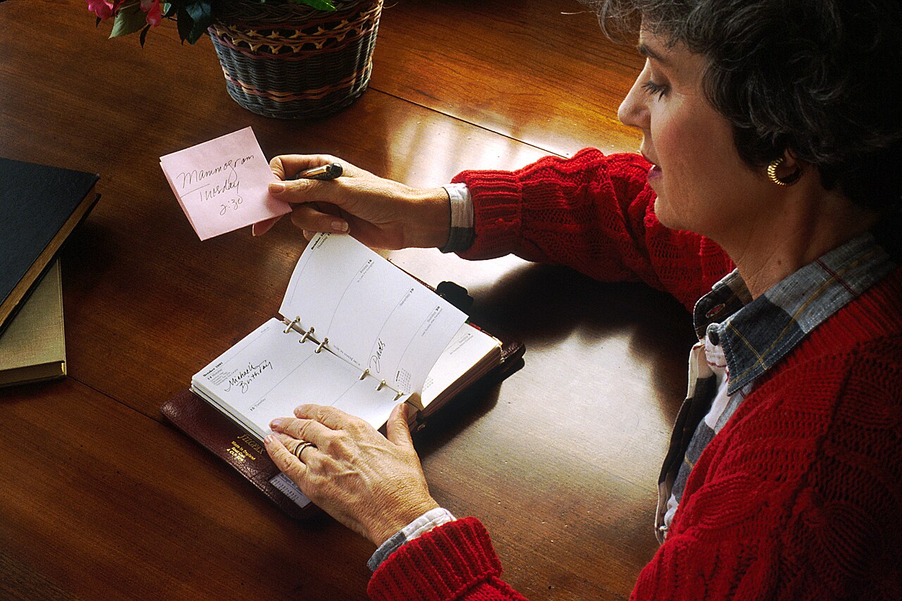A woman writing in a planner at a desk