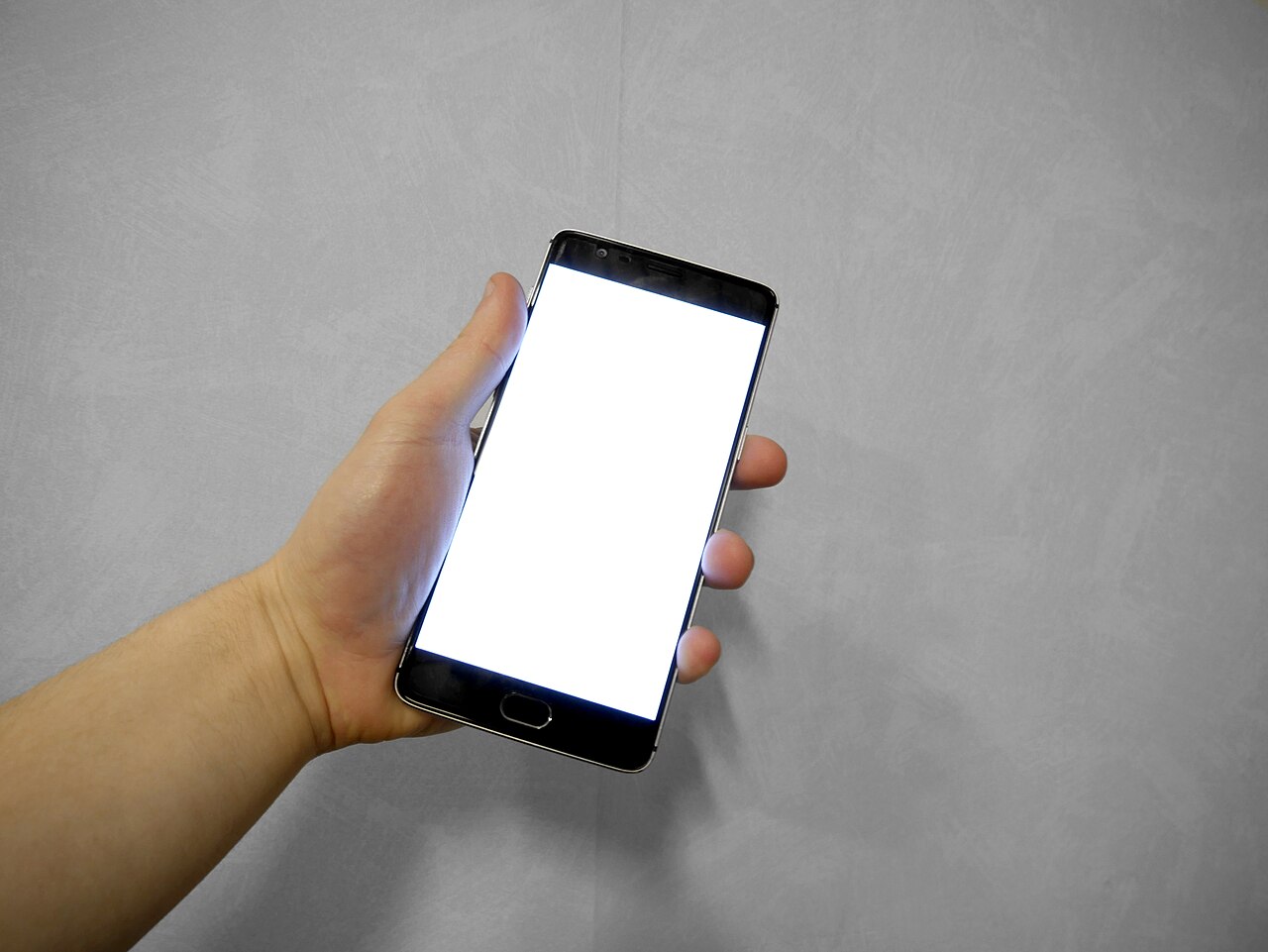 A hand holding a smartphone with a glowing screen
