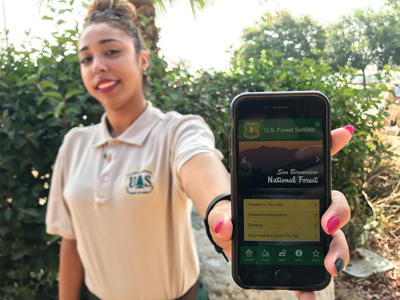 A woman holding up a smartphone showing an app