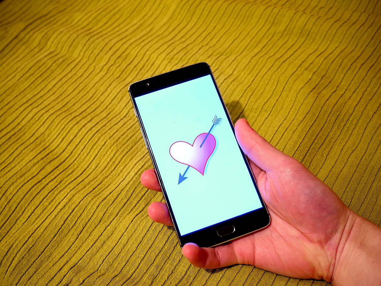 A hand holding a smartphone showing a heart