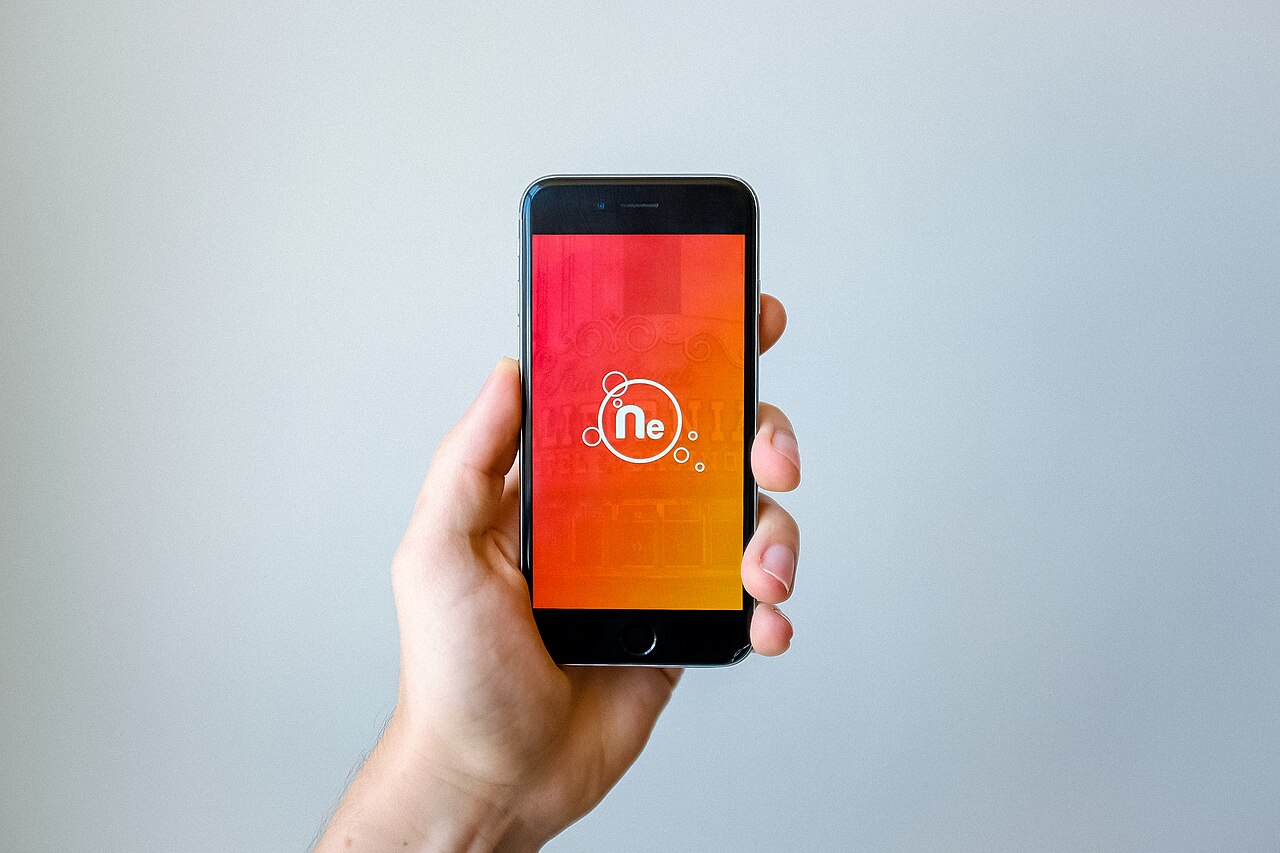 A hand holding a smartphone showing an app interface