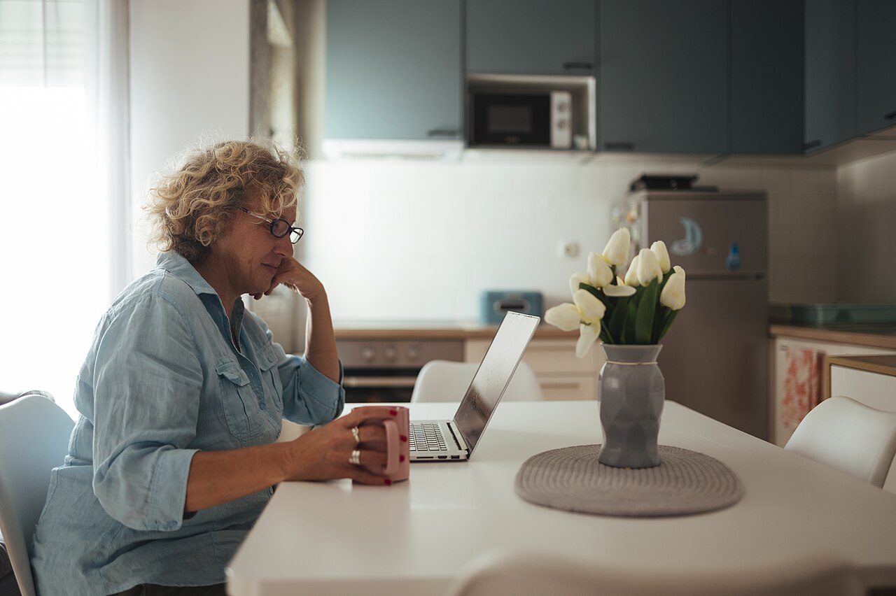 A woman working on a laptop at a kitchen table