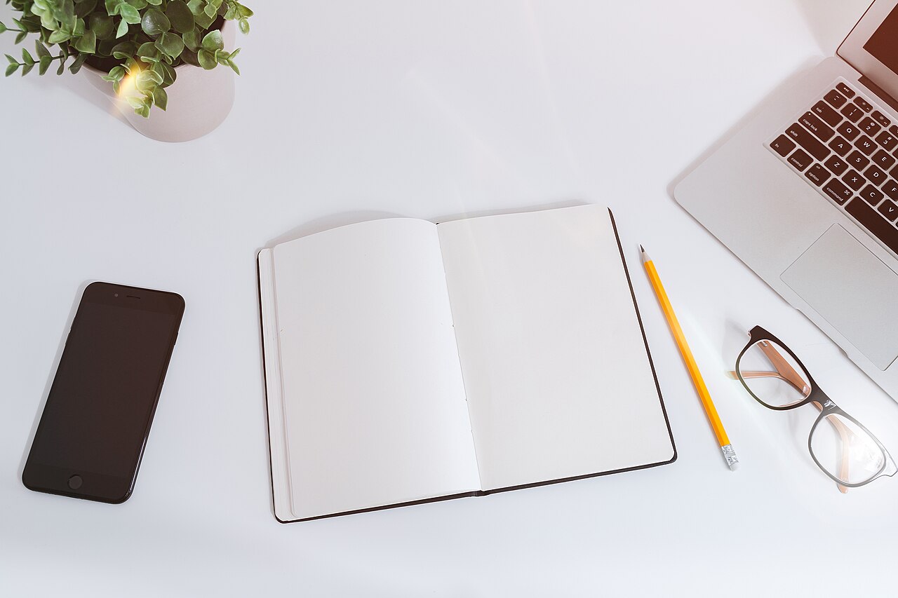 Notes, a smartphone and a laptop on a white table