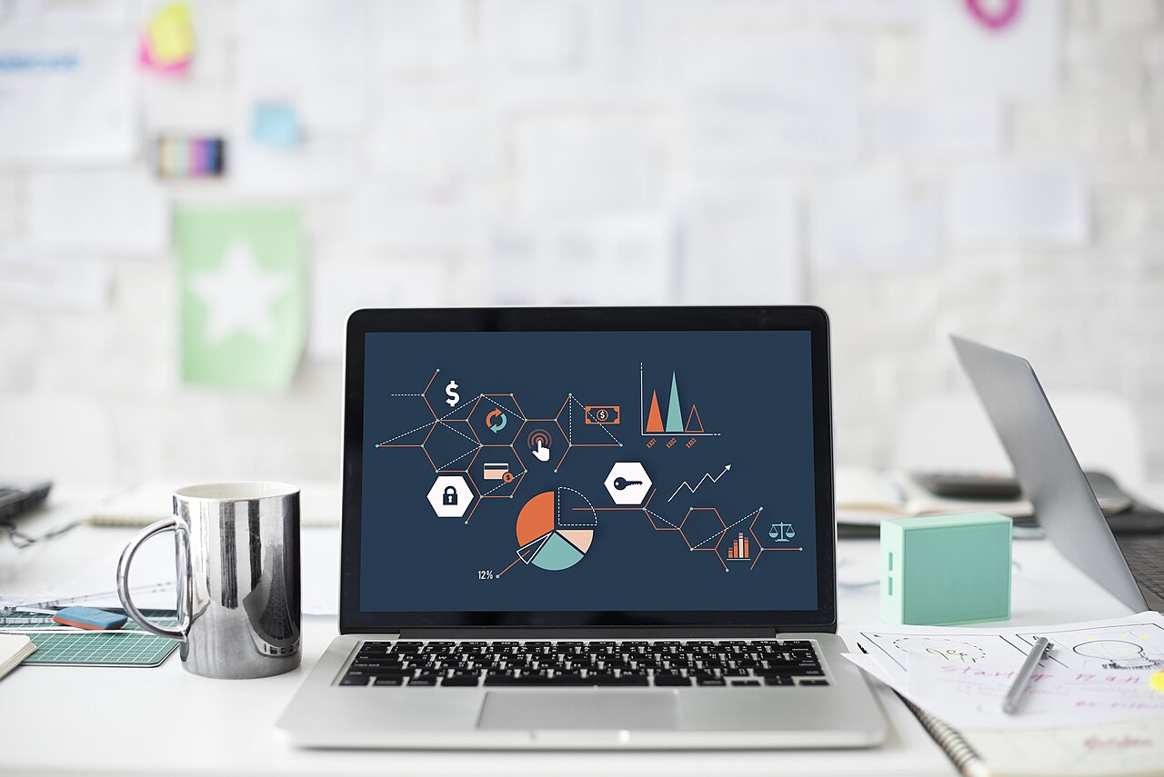 A laptop showing charts on a cluttered desk