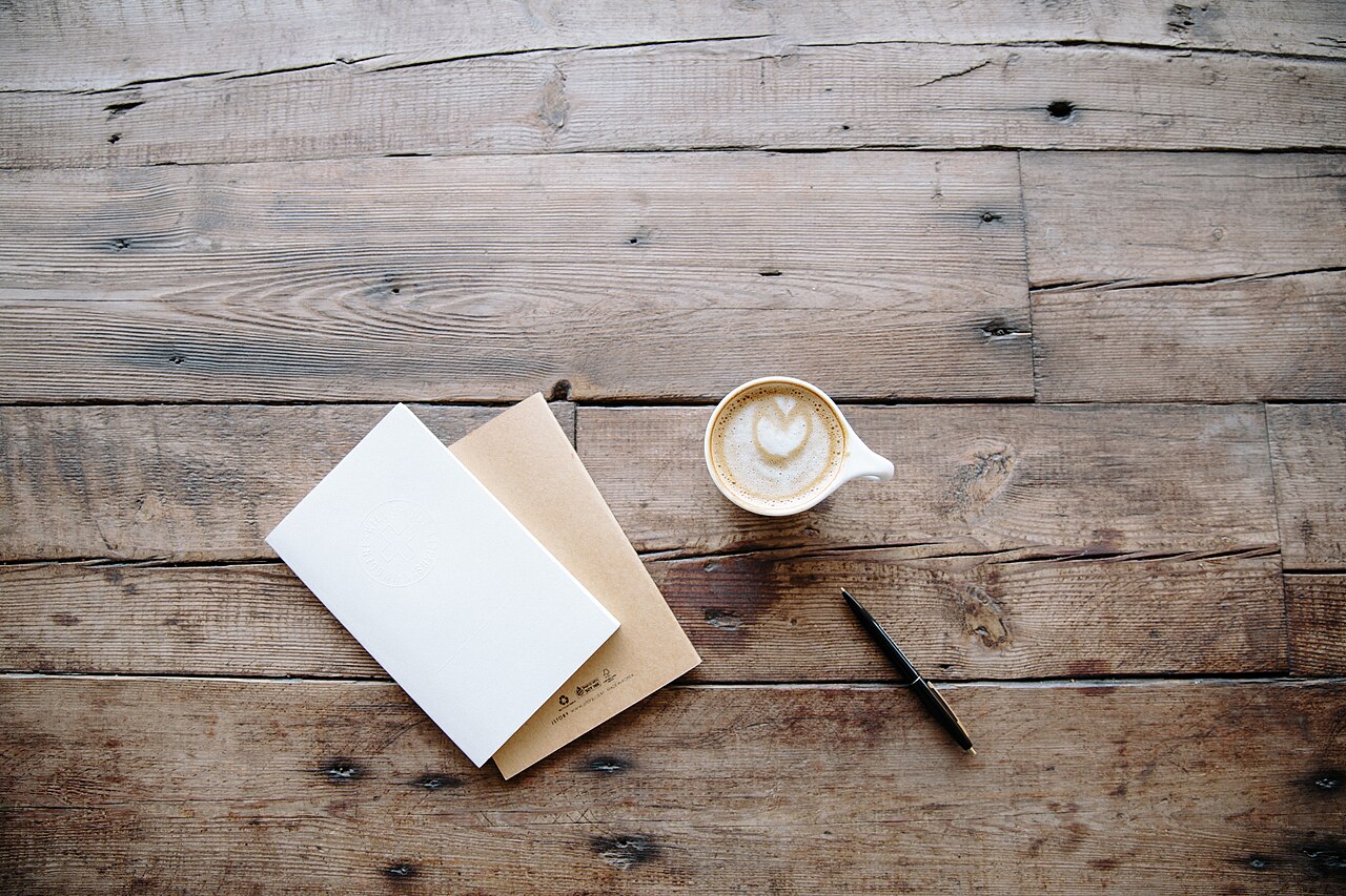 Coffee, notebooks and a pen on a table