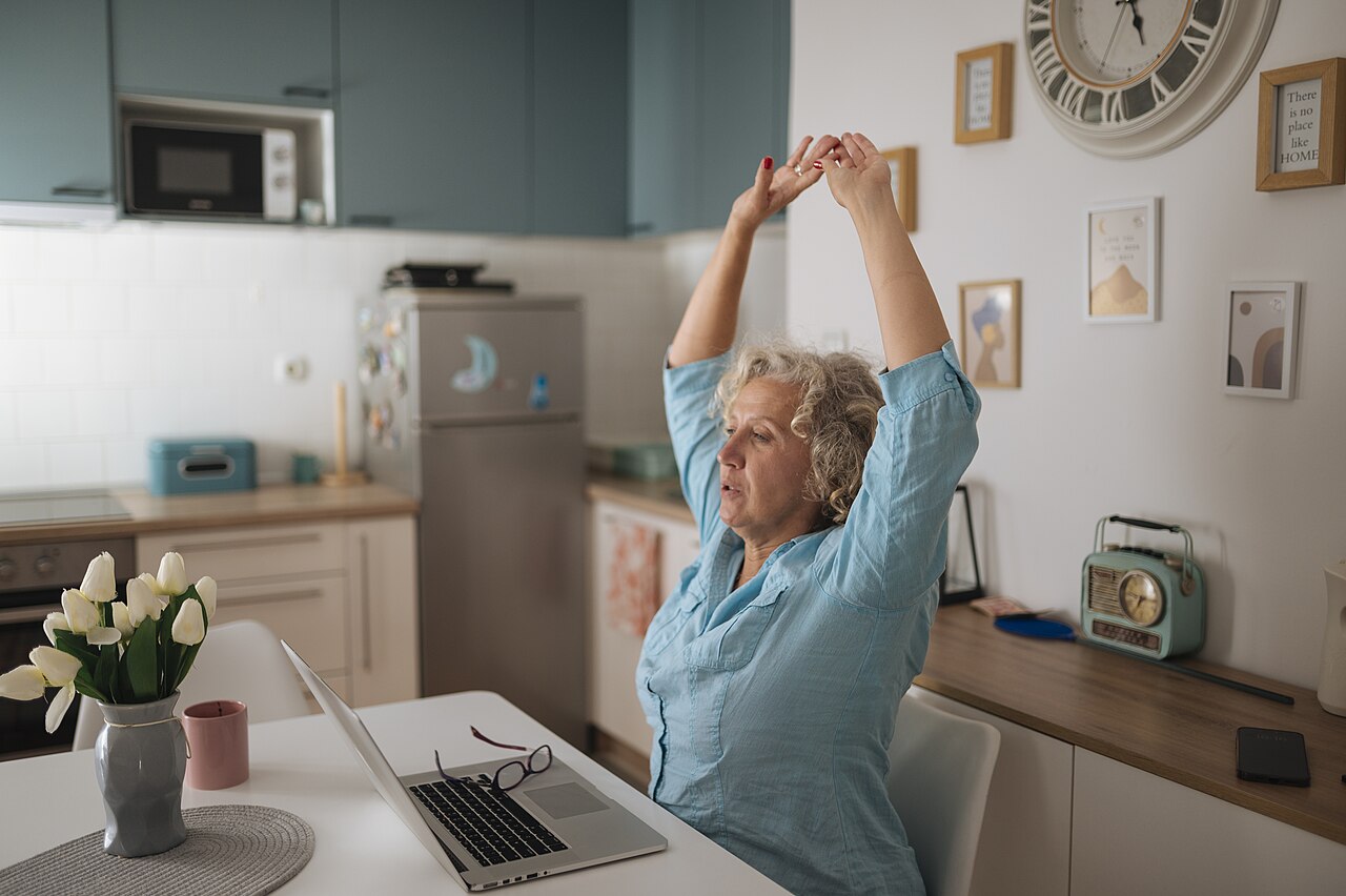 A woman stretching at her desk while working at home